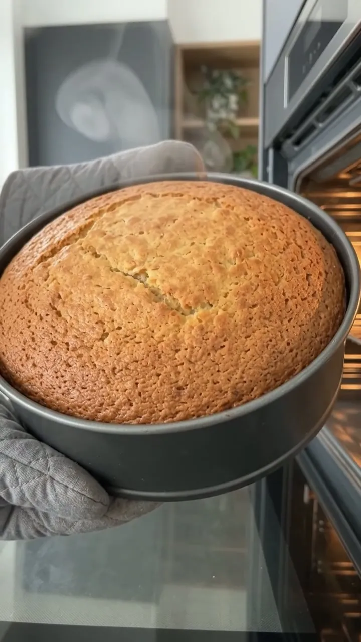 The carrot cake being lifted from the oven in its tin